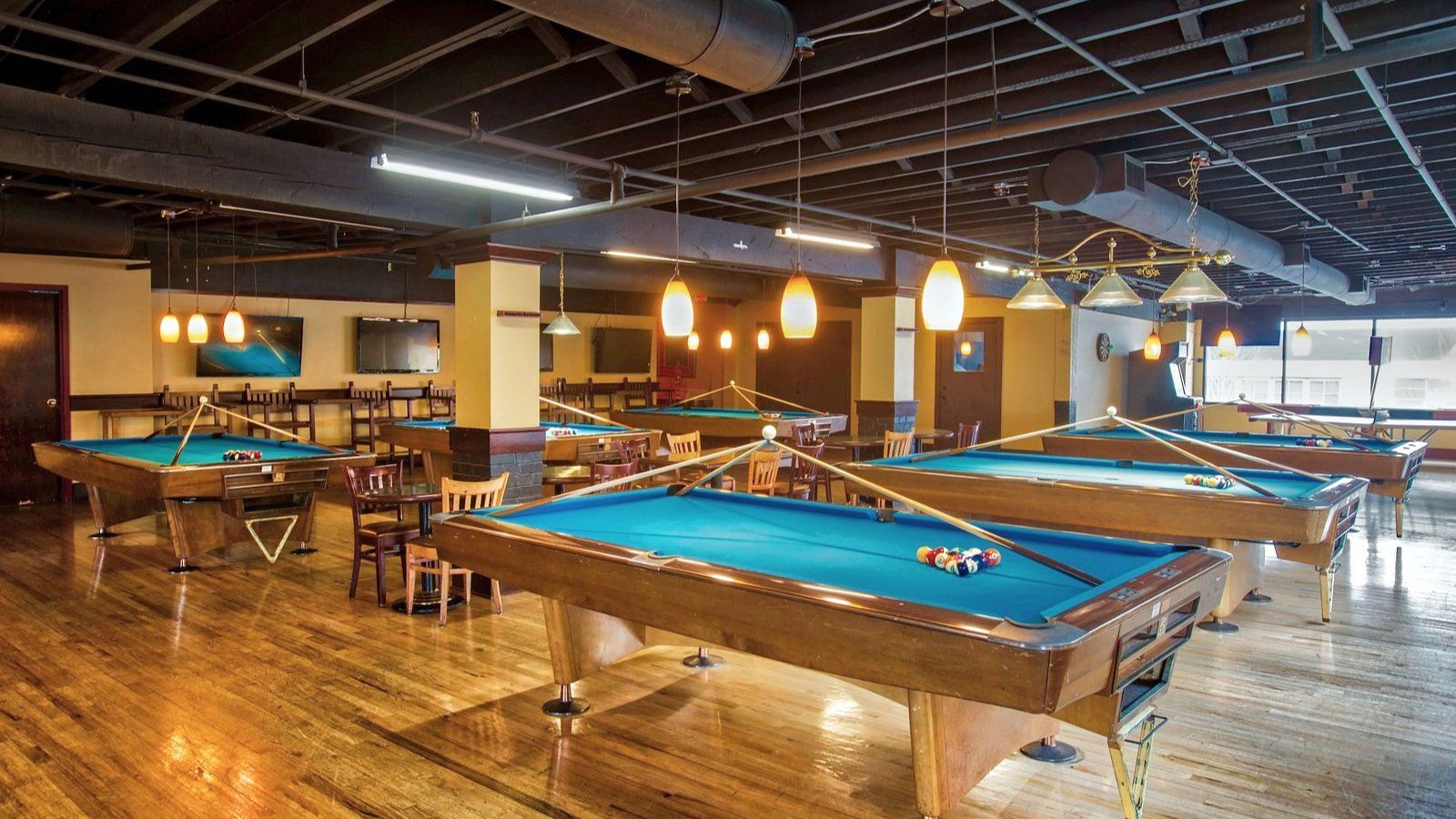 A pool hall filled with pool tables and chairs.