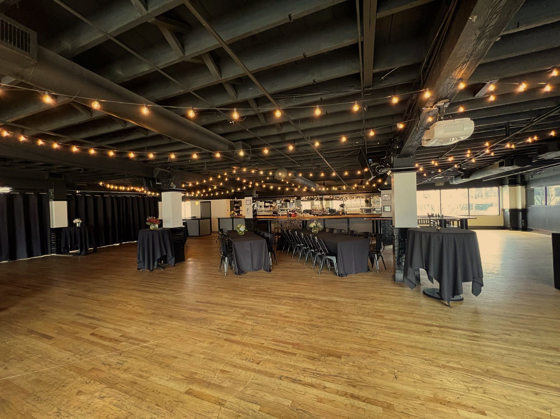 A large room with tables and chairs and a string of lights hanging from the ceiling.