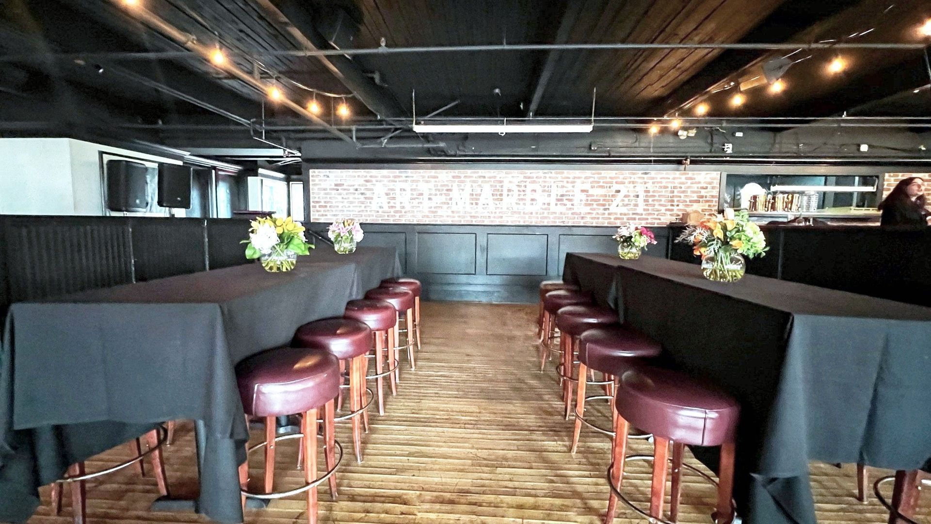 A long table with a black tablecloth and stools in a room.