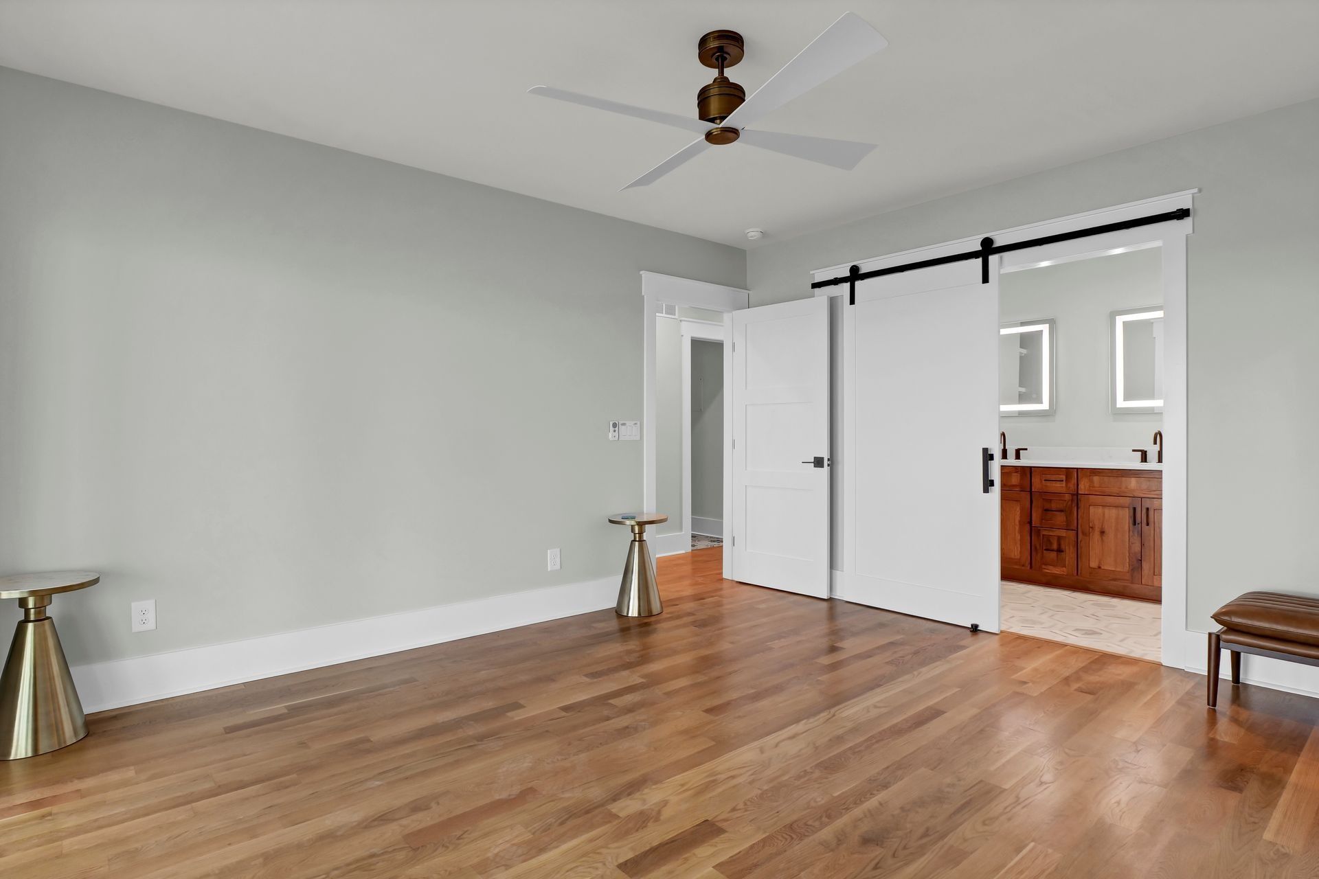 Empty bedroom with wood floor, white sliding door, and light gray walls.