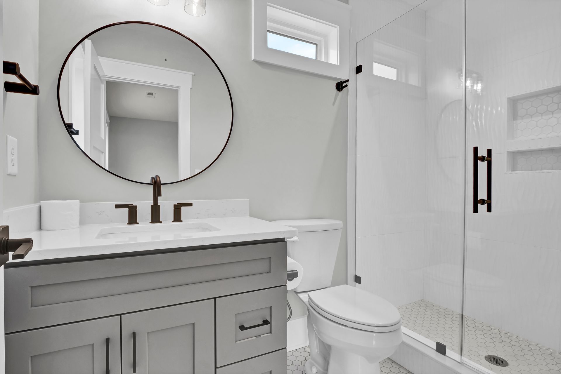 Gray and white bathroom with a vanity, toilet, and glass shower.