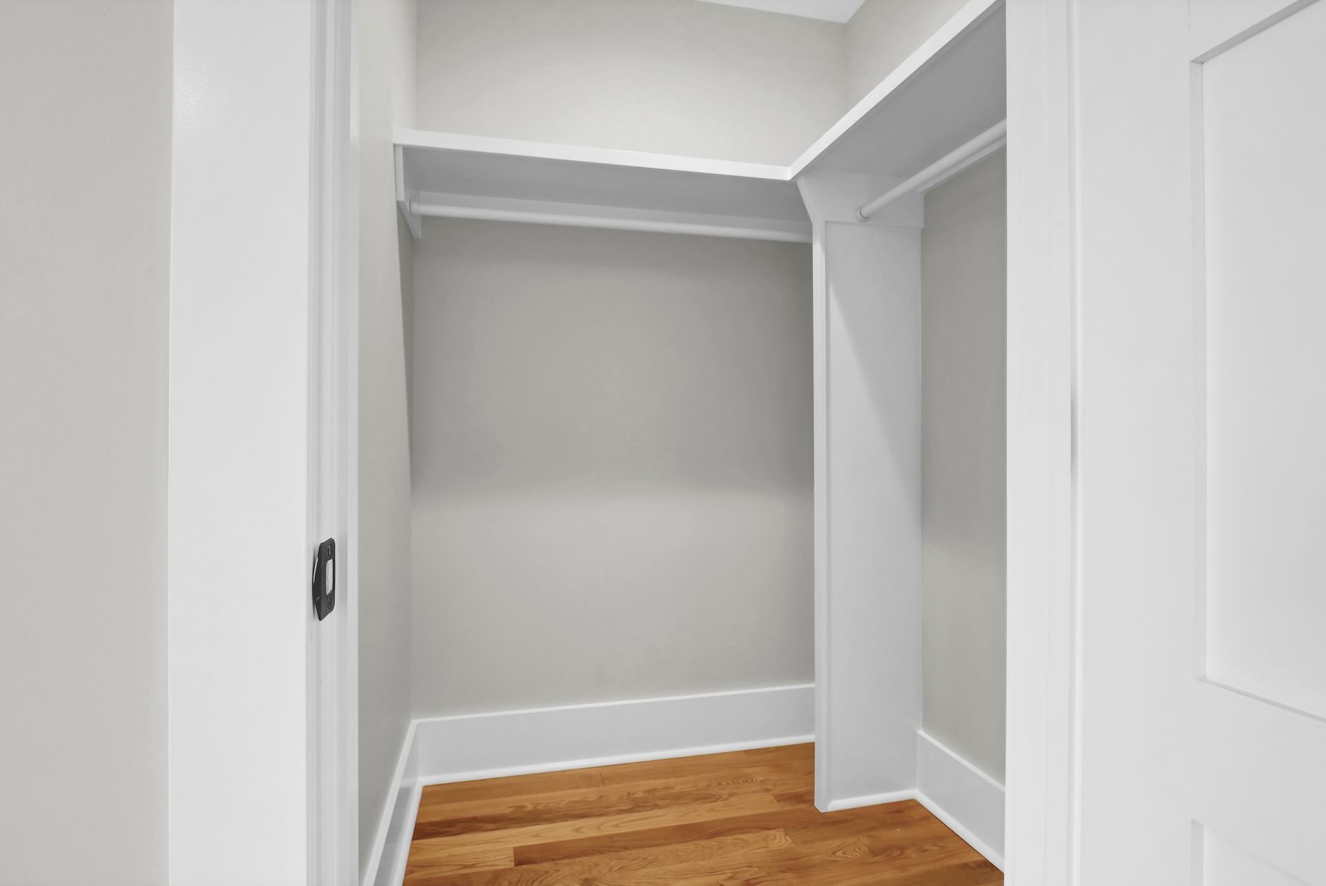 Empty closet with white trim and gray walls. Wooden floor.