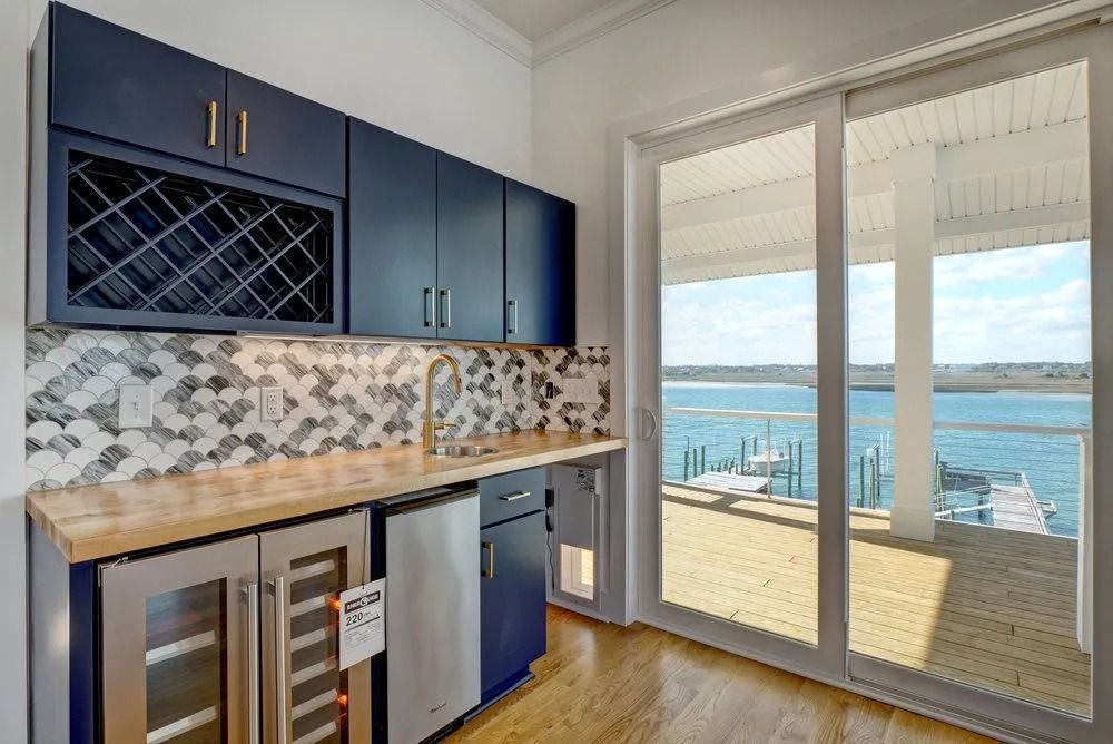 Navy blue bar area with wine rack, countertop, and view of water through sliding doors.