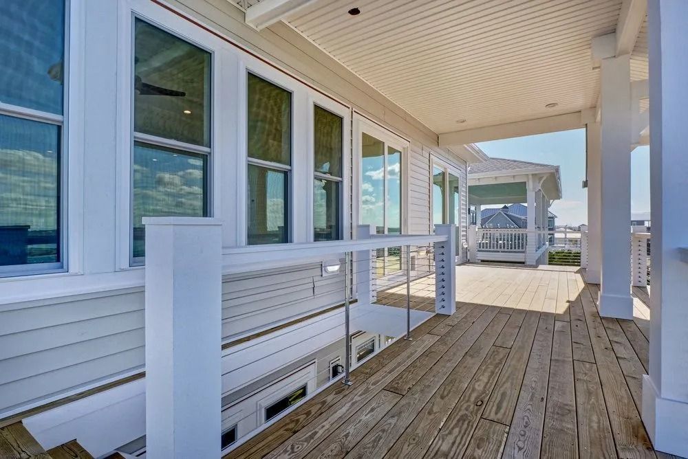 White porch with wooden floor and windows overlooking a gazebo.