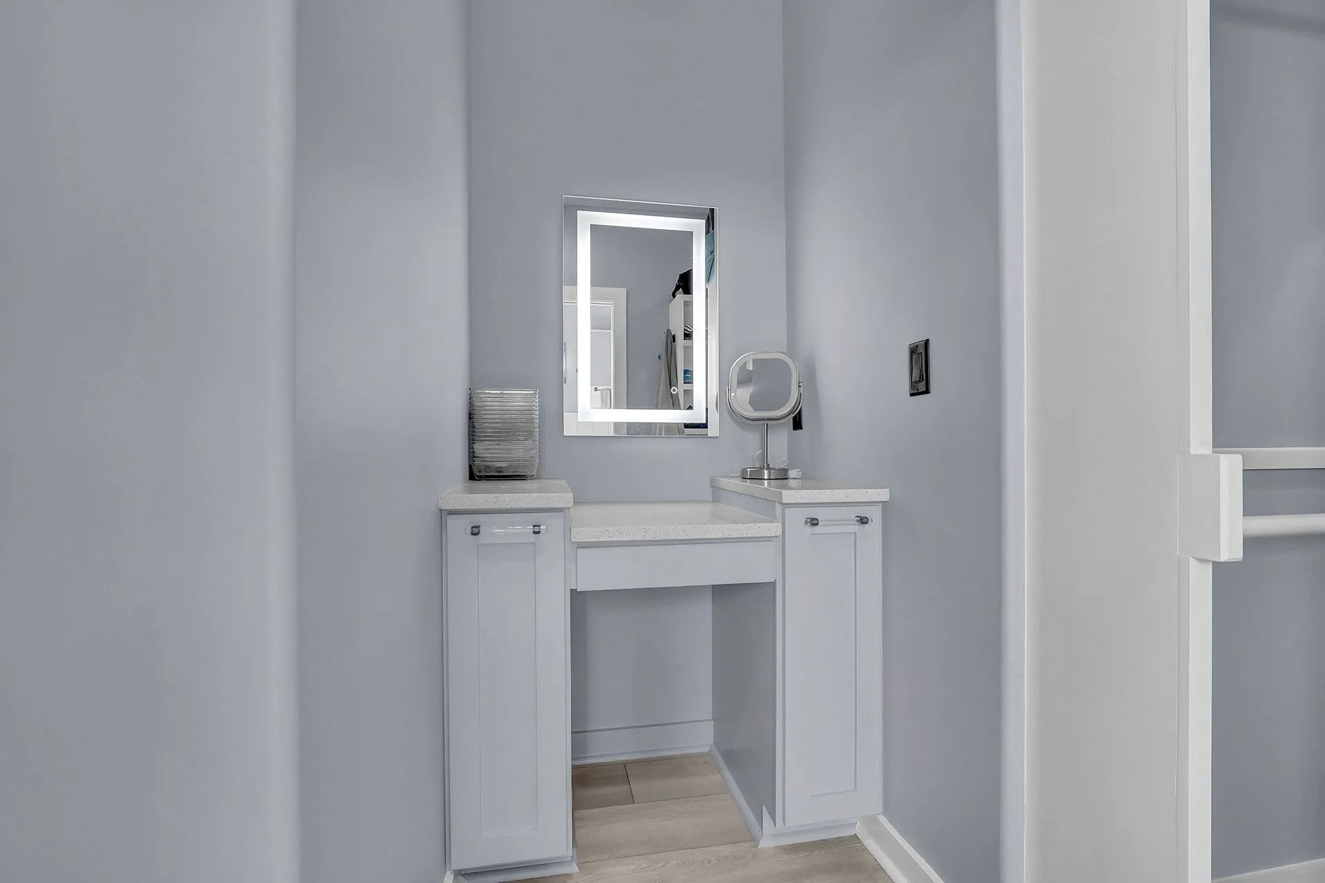 Vanity area with mirror, lights, and small table; light blue walls and white trim.