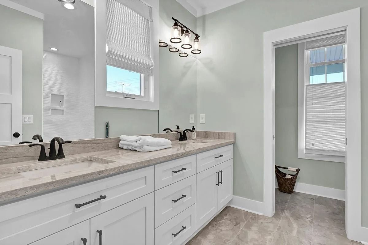 Bathroom with white vanity, pale green walls, and a window with blinds.