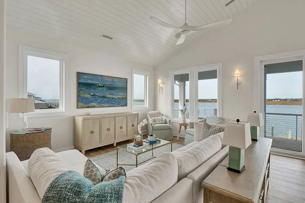 Bright living room with water view, white walls, sofa, coastal decor, and a large abstract painting.