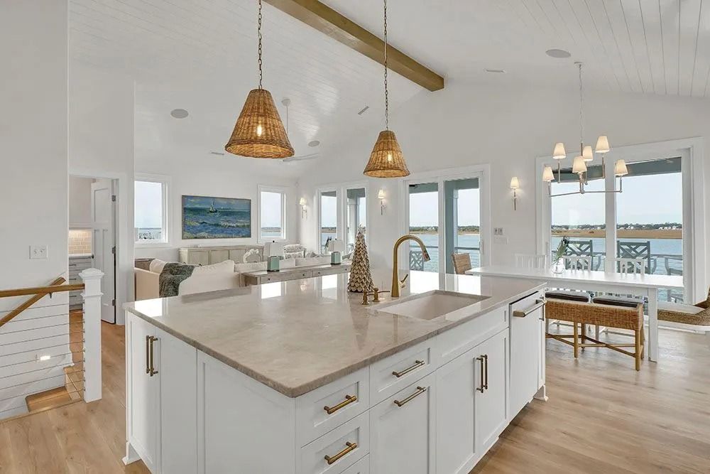 Bright kitchen with white cabinets, island, and seating area overlooking water.