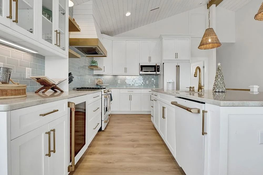 White kitchen with wood floors, gold accents, and a light blue tile backsplash.