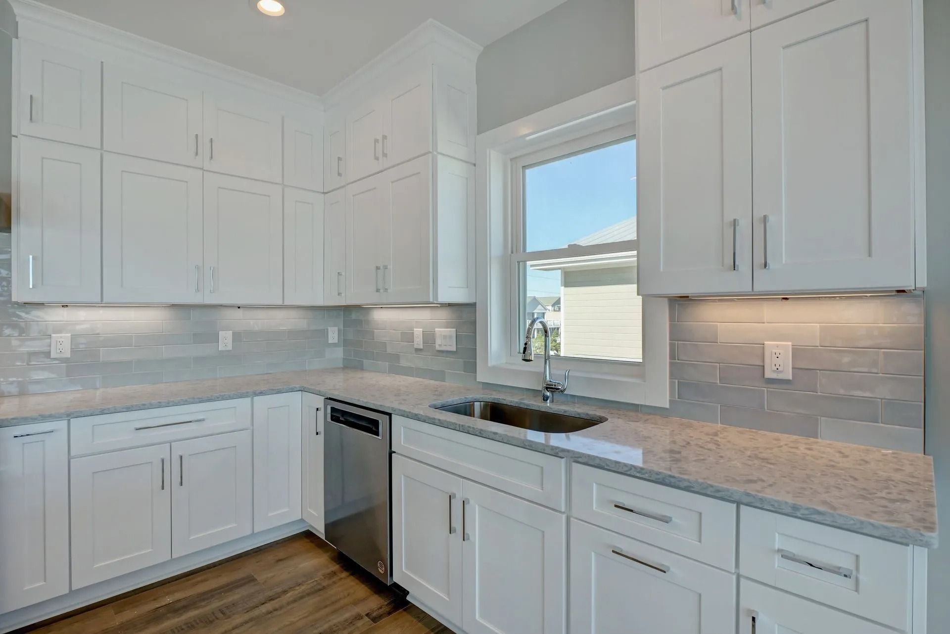 White kitchen with stainless steel appliances, light countertops, and a window.