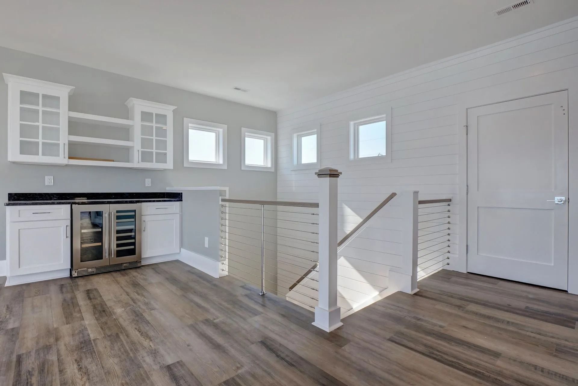 Bright loft space with wet bar, cabinets, and wood-look flooring. Light gray and white color scheme.