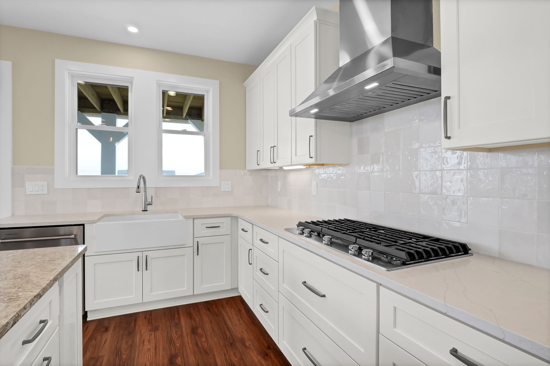 White kitchen with cabinetry, stainless steel range hood, stove, and farmhouse sink.