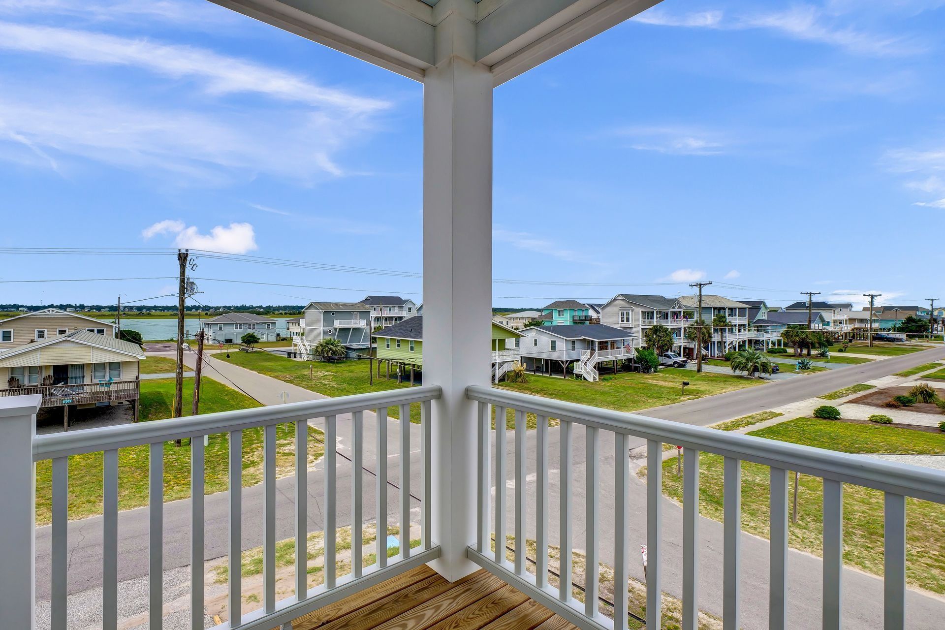 Balcony overlooking coastal houses and roads under a blue sky.