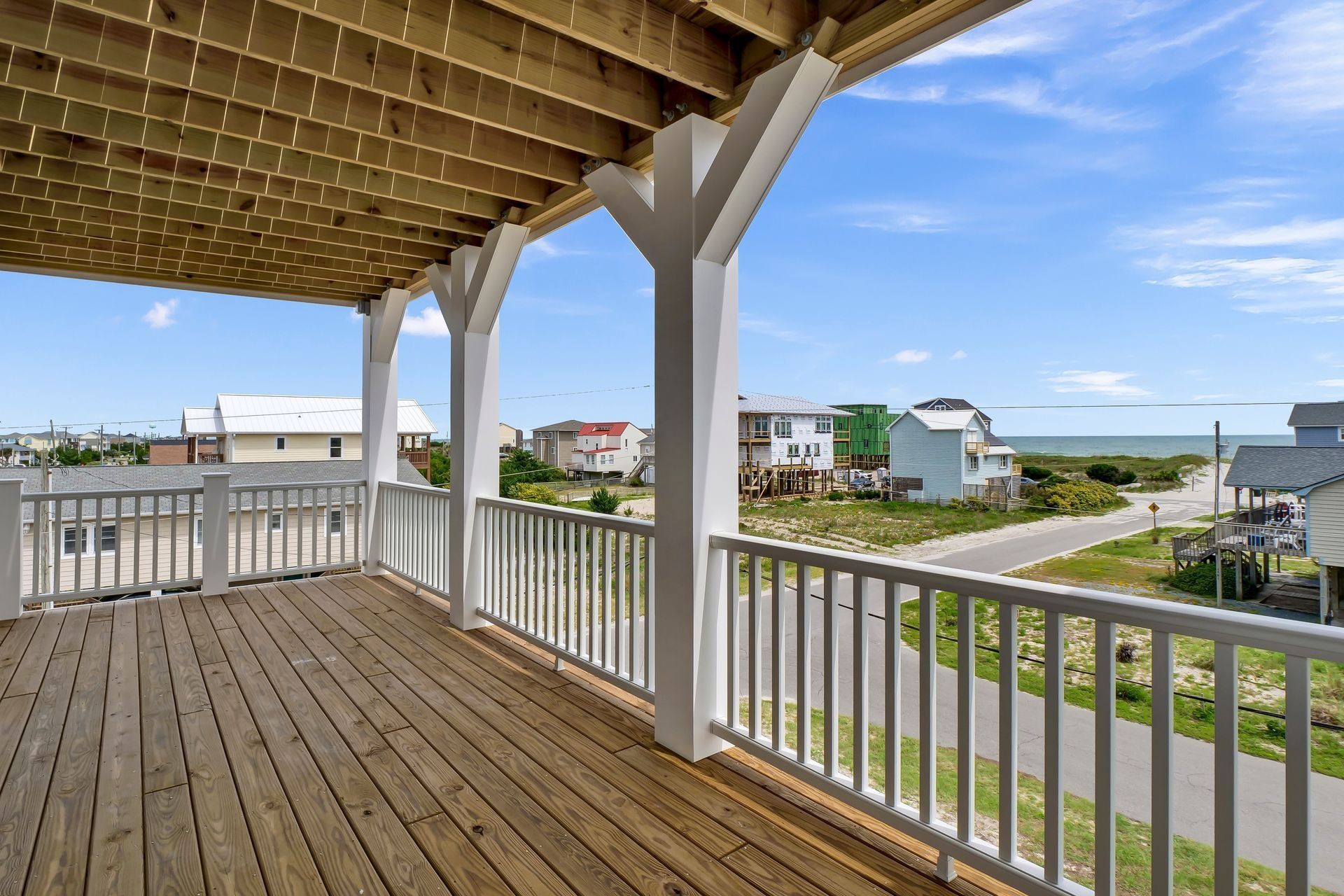 Deck overlooking a coastal neighborhood with blue sky and ocean view.