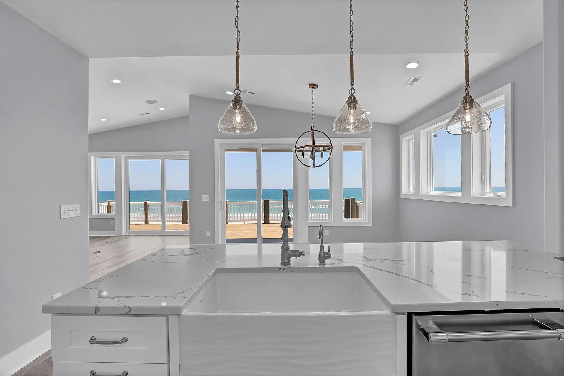 Kitchen with white countertops, sink, and ocean view through windows.