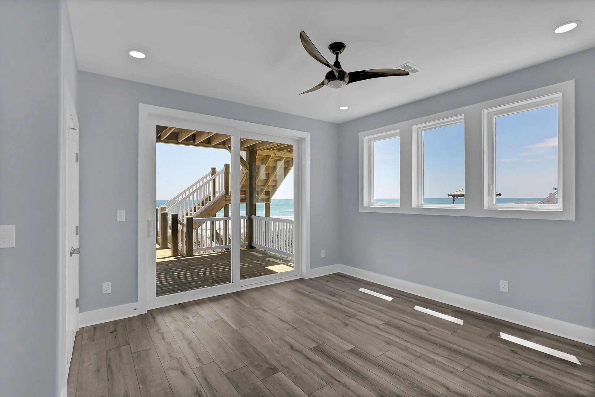 Beachside room with ocean view; sliding glass door opens to deck, windows on the right.