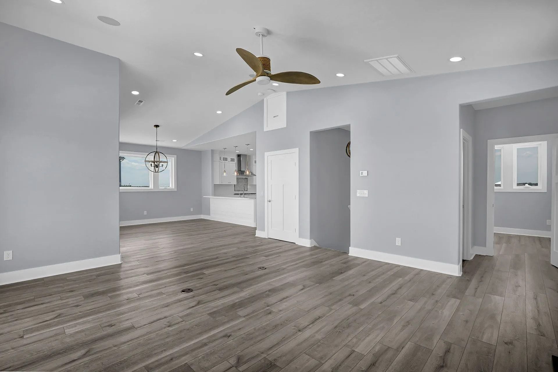 Empty living room with wood floors, pale blue walls, and a ceiling fan.