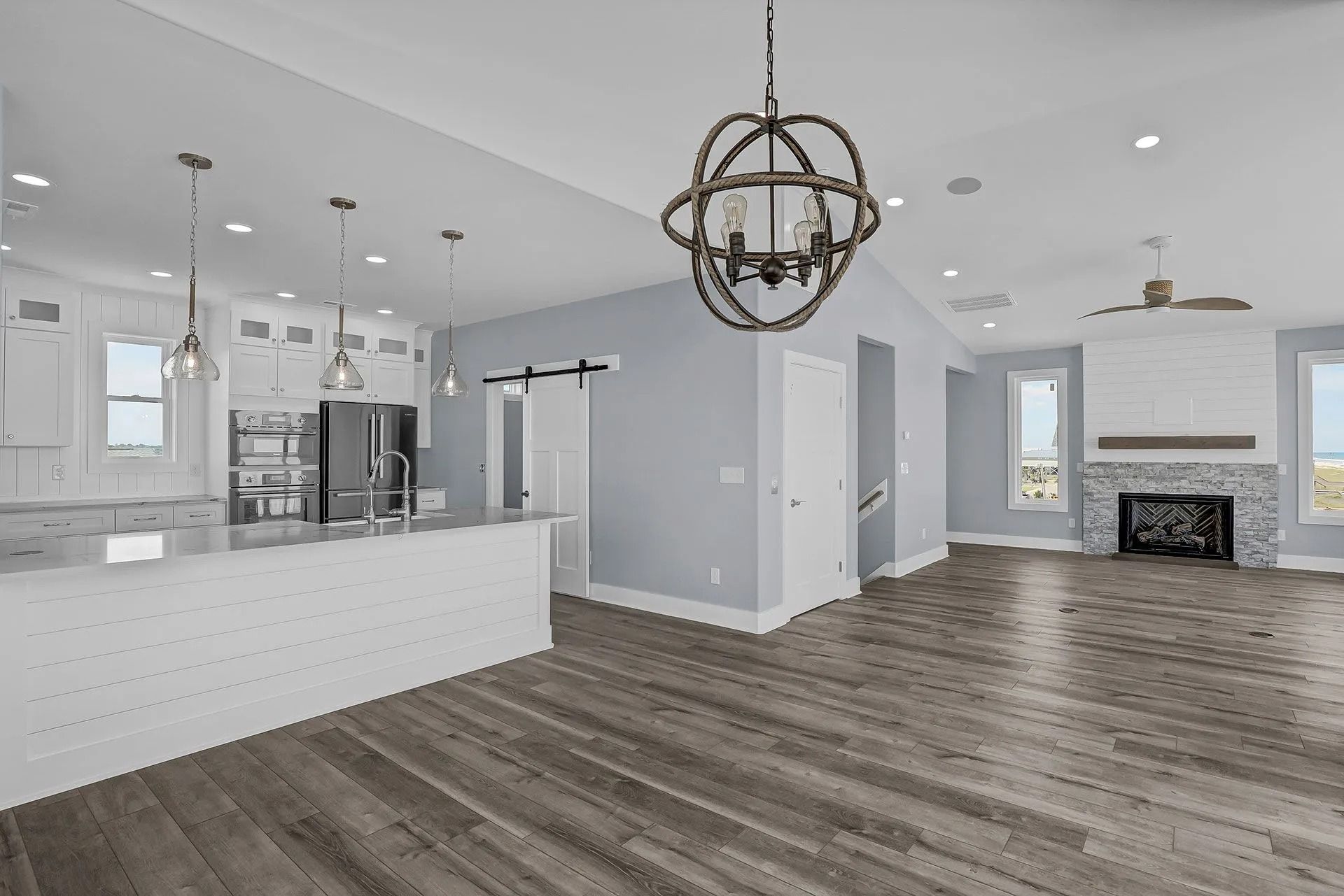 Spacious, modern kitchen and living room with hardwood floors, a fireplace, and light blue walls.