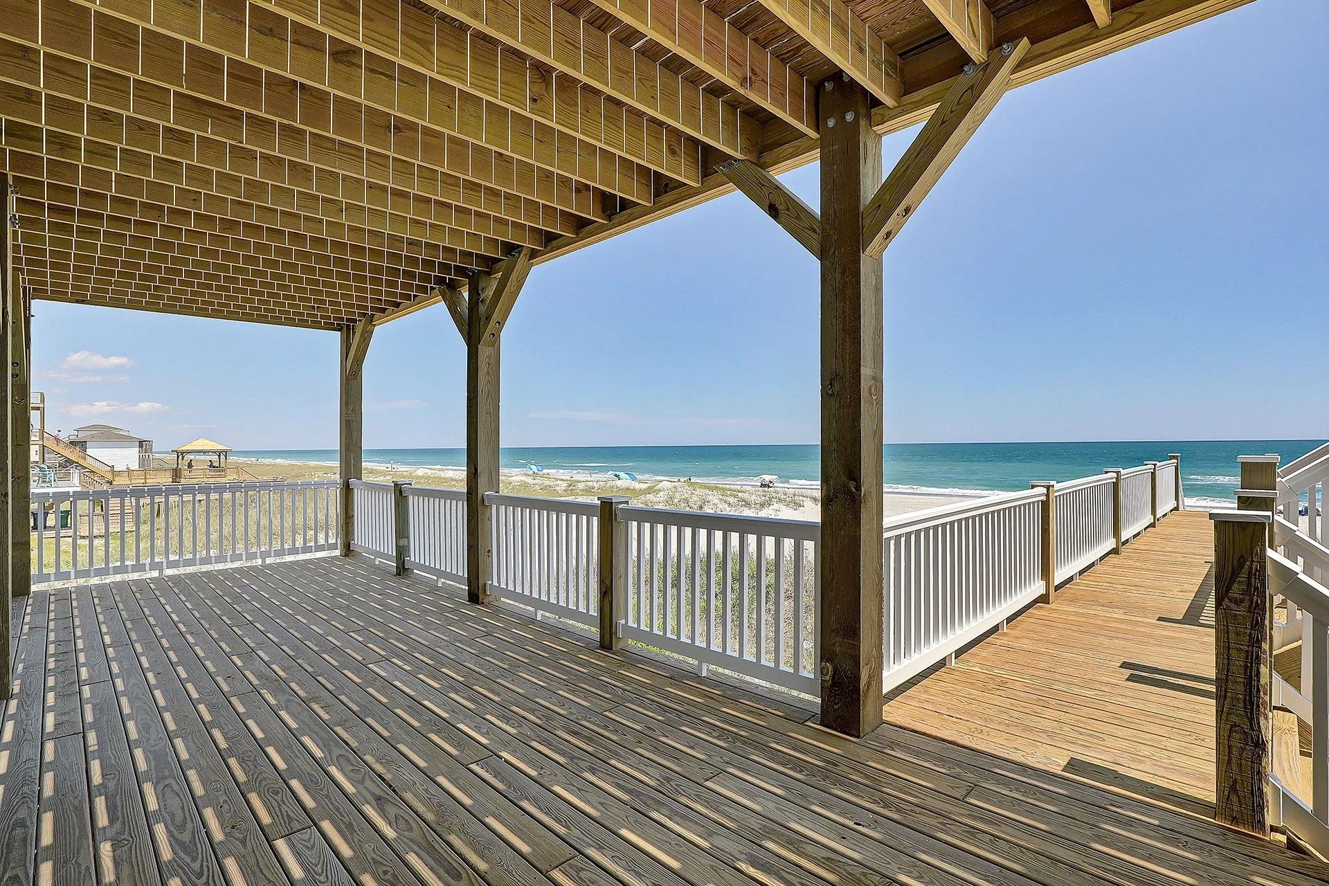 Wooden deck overlooking a beach and ocean on a sunny day.