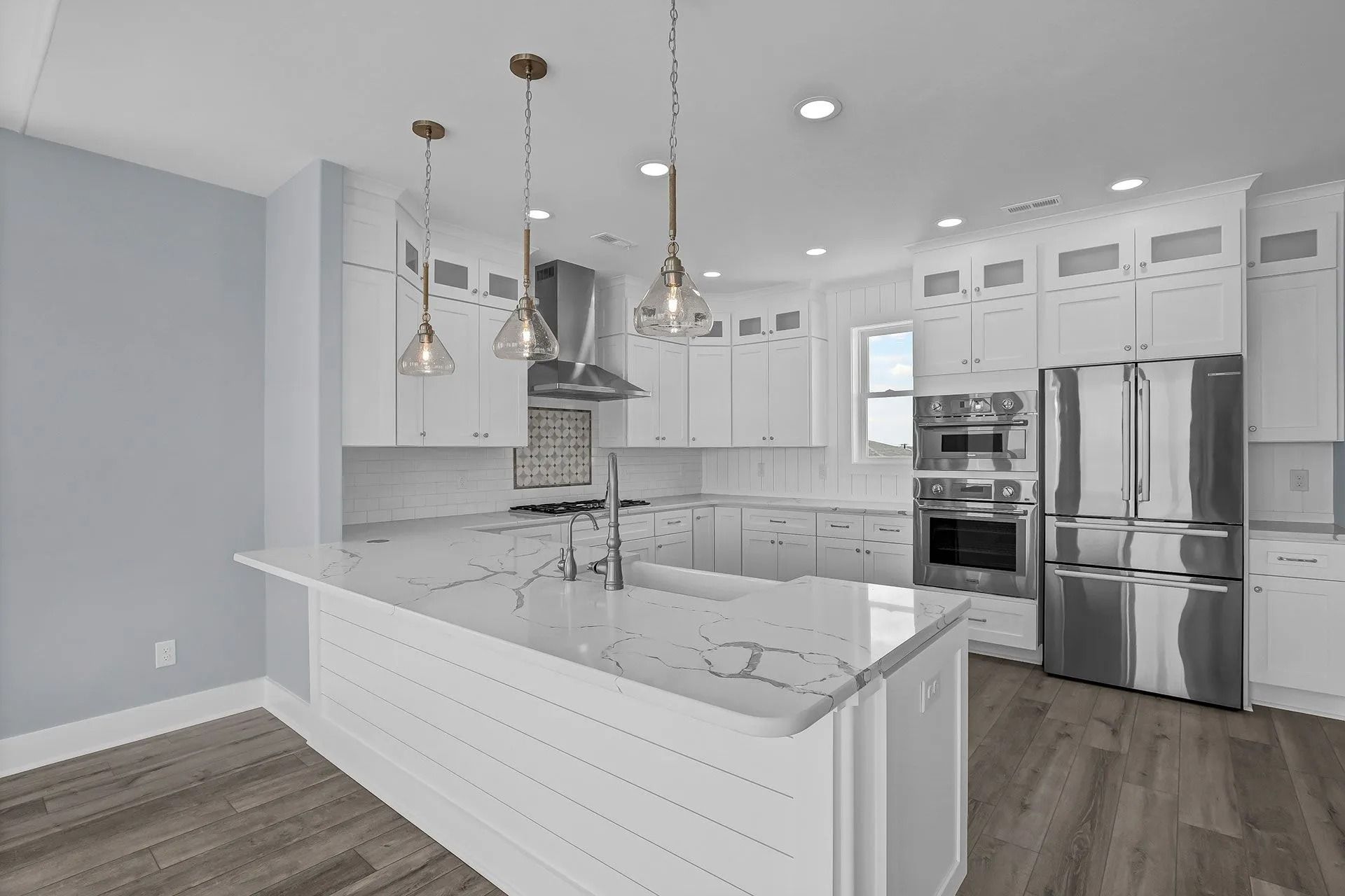 Bright white modern kitchen with stainless steel appliances and light blue walls.