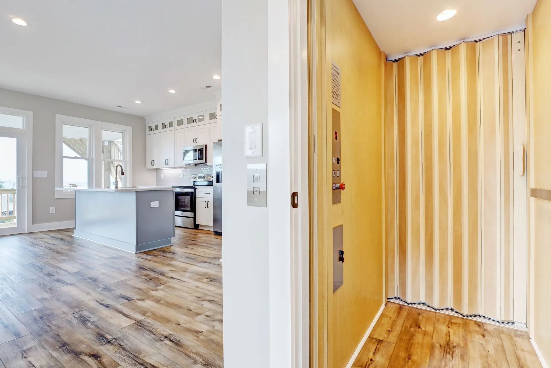Open doorway to kitchen and home elevator. Elevator has yellow walls and a beige curtain.