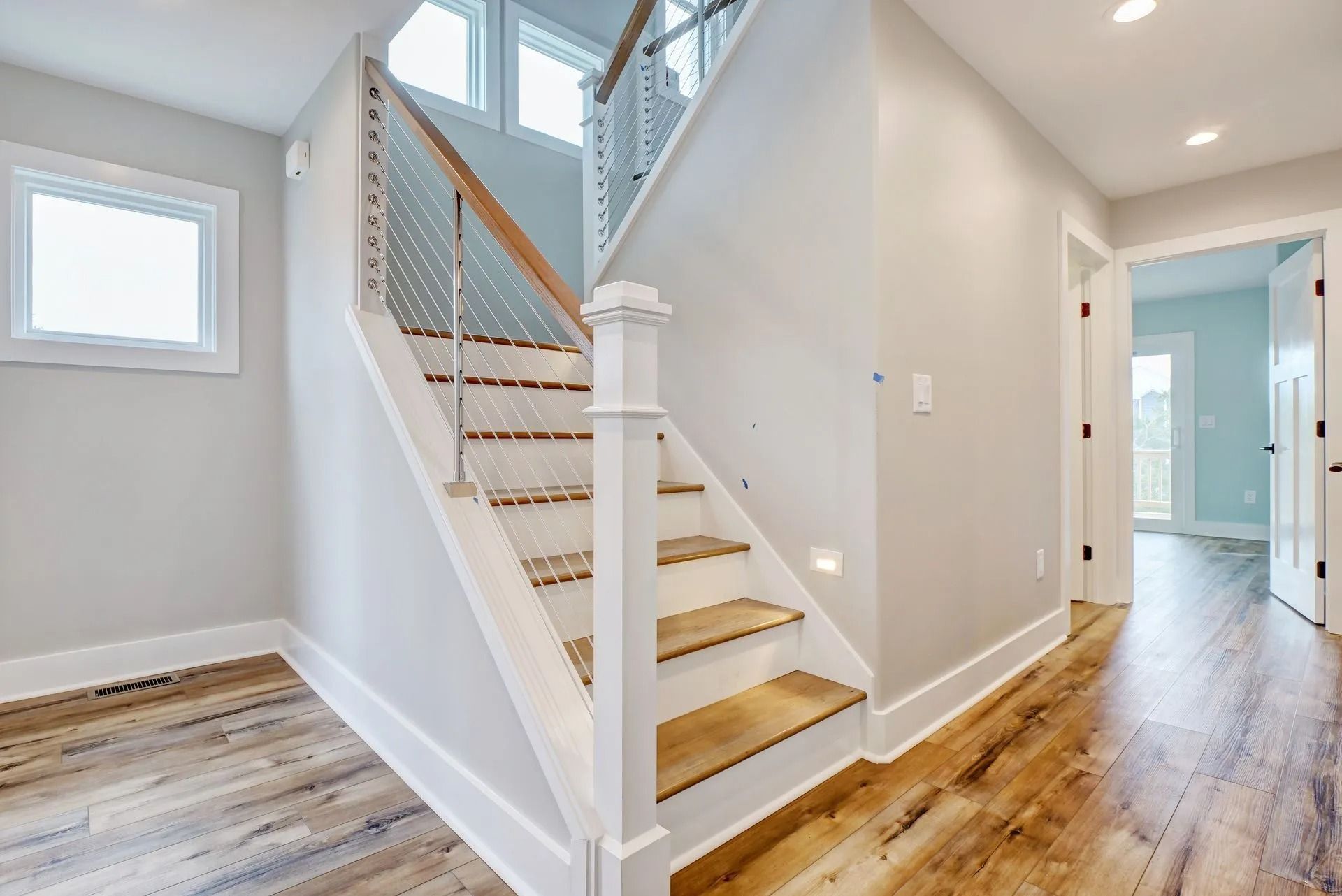 Staircase with light wood steps, white railing, and grey walls leading to a second floor.