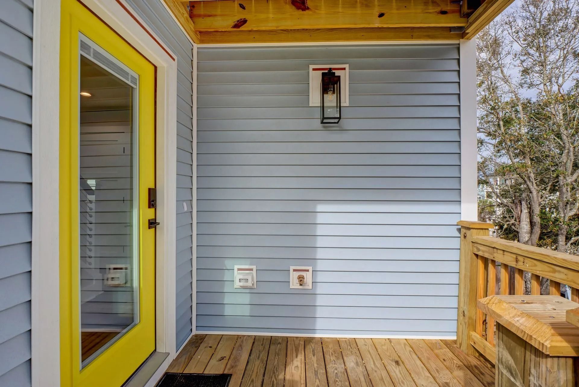 Blue house exterior with yellow front door, porch, wood deck, and laundry hookups.