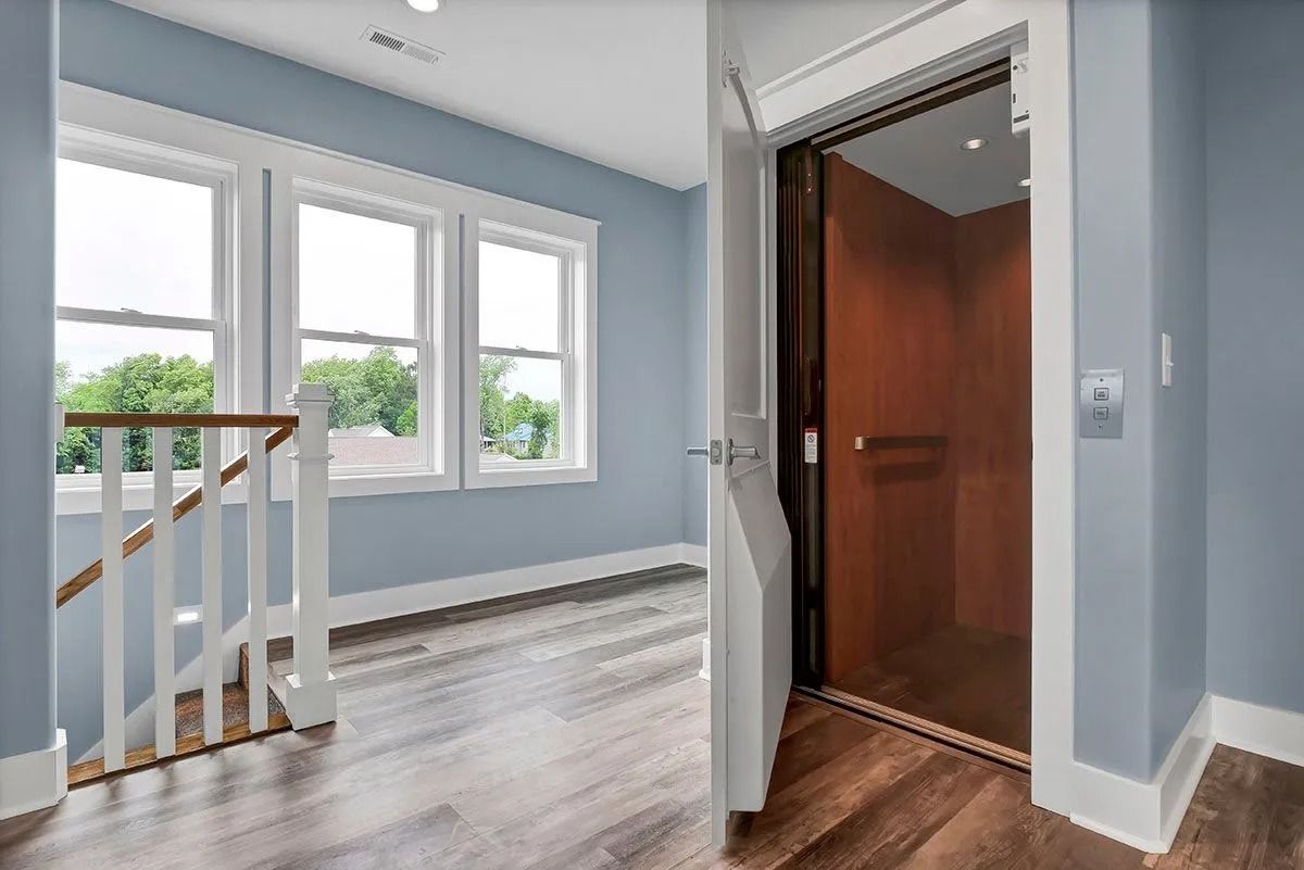 Hallway with blue walls, windows, and an open elevator. Wooden floors and white trim.