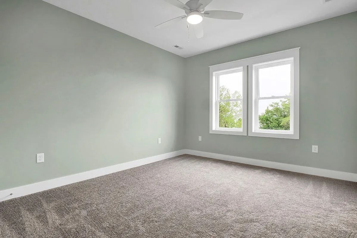 Empty room with gray carpet, light green walls, white trim, and a window.
