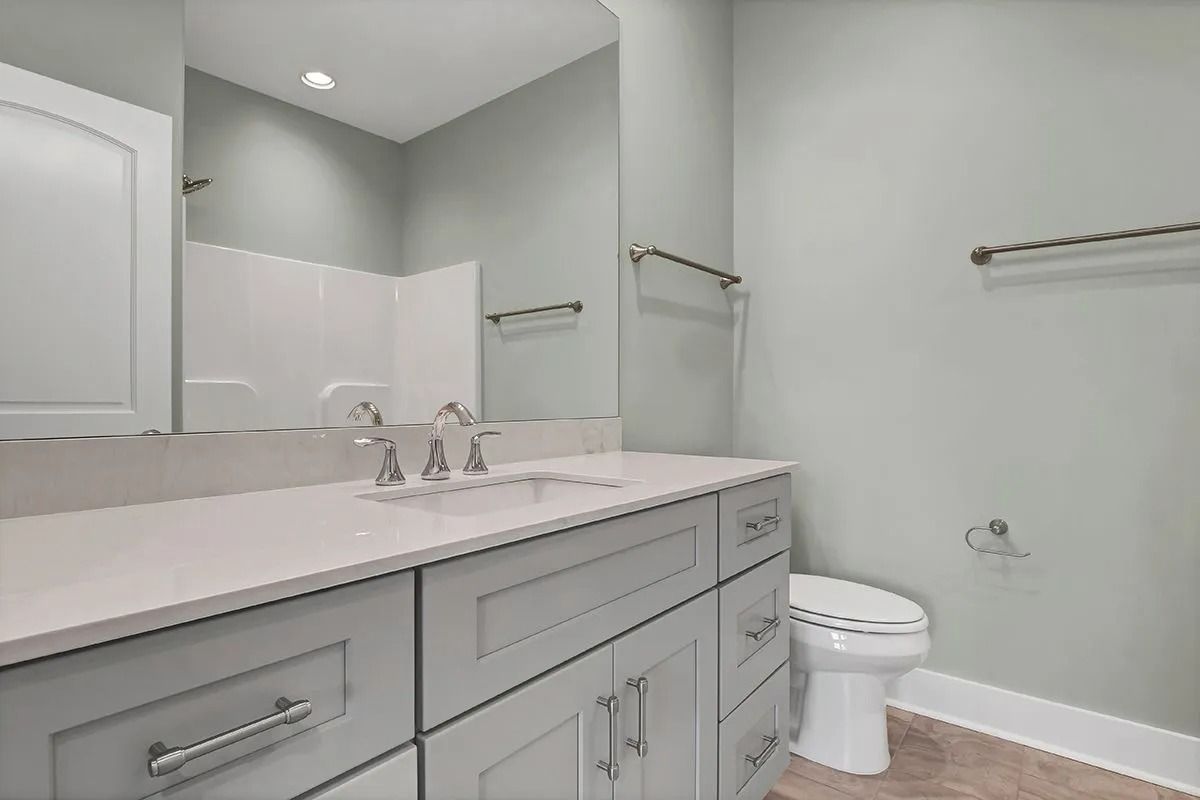 Bathroom with gray cabinets, white countertop, toilet, and light green walls.