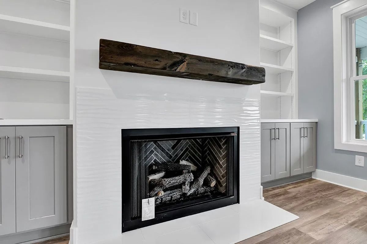 White fireplace with dark mantel and built-in white shelves and gray cabinets.