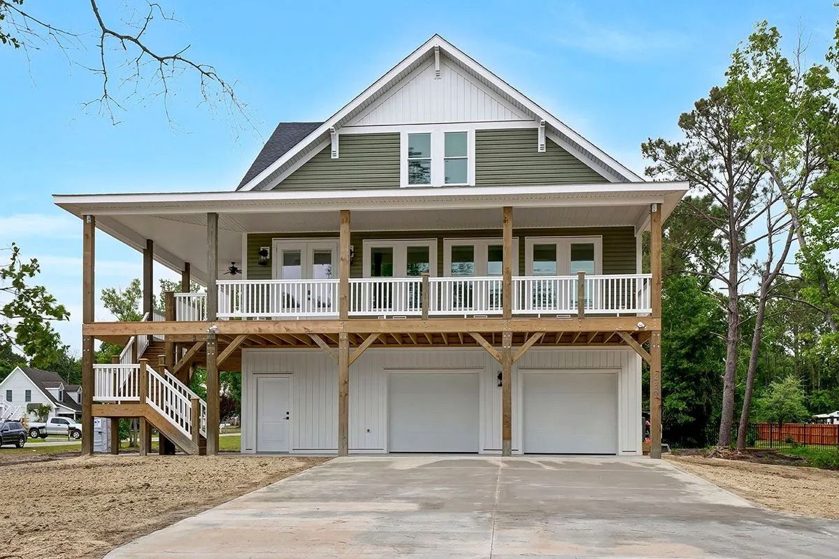 Two-story house with green siding, white trim, and a porch over a garage.