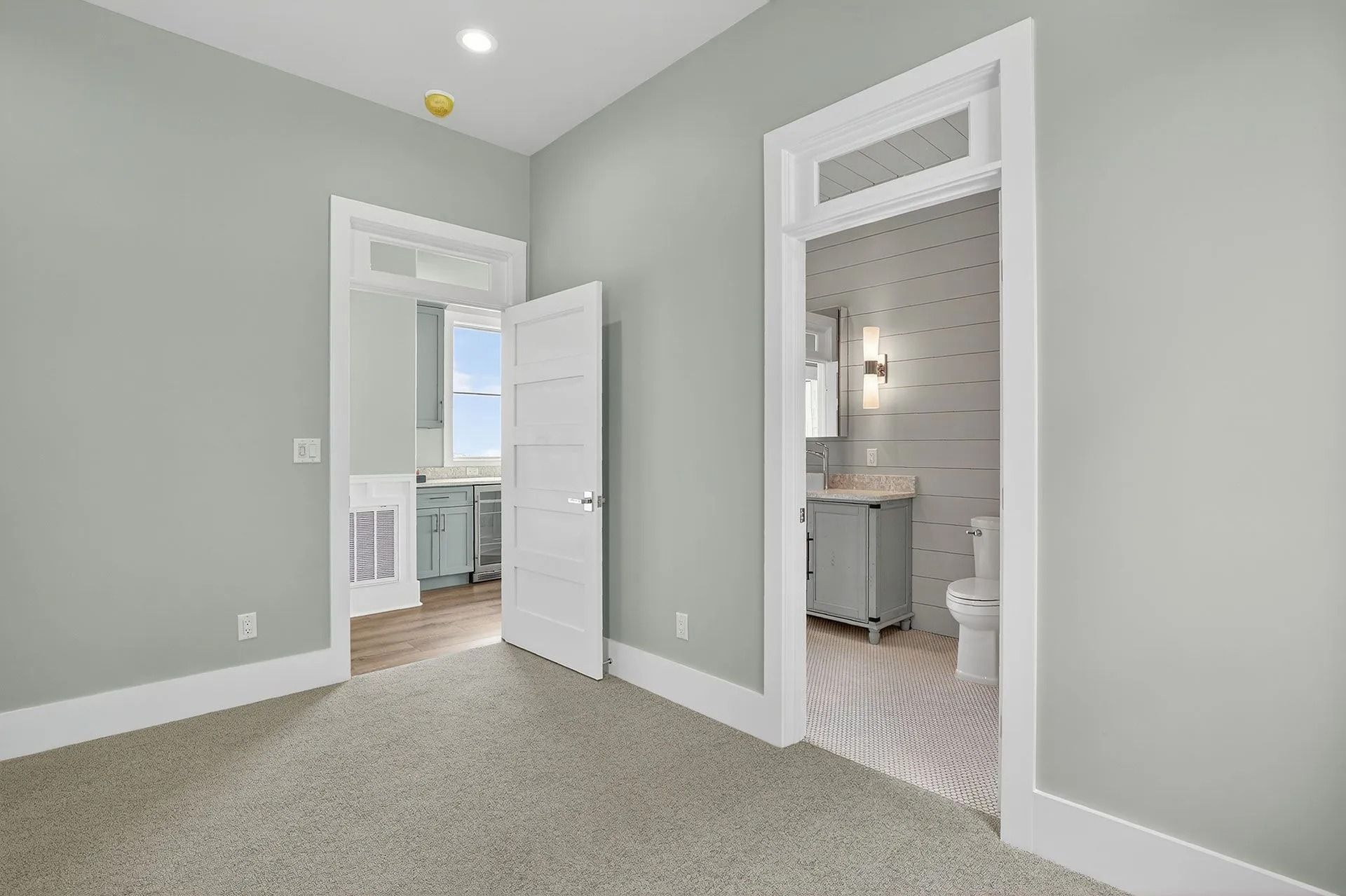 Empty bedroom with gray walls, two doorways leading to a bathroom and another room.