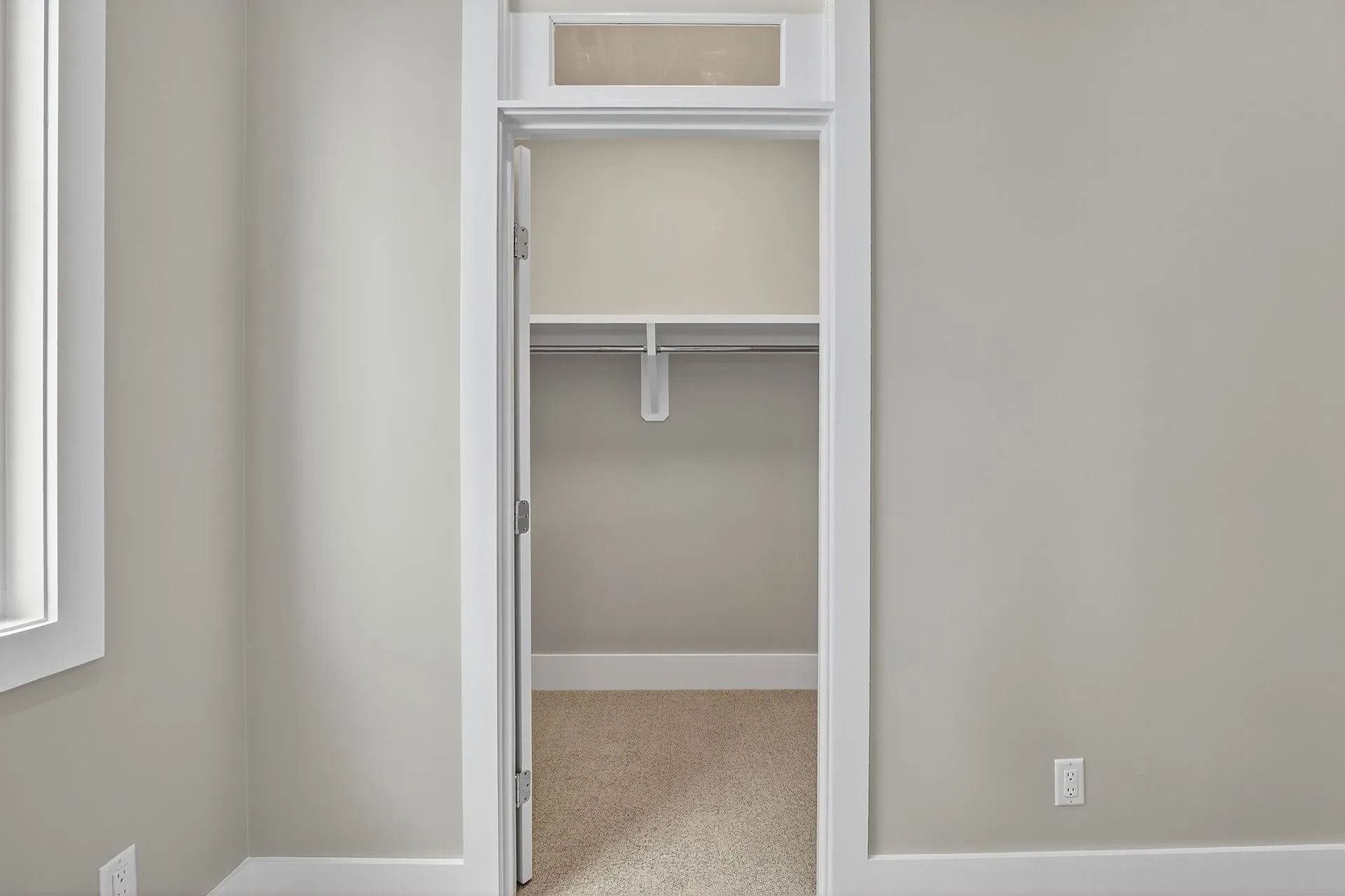 Empty closet with white trim and a beige carpet.