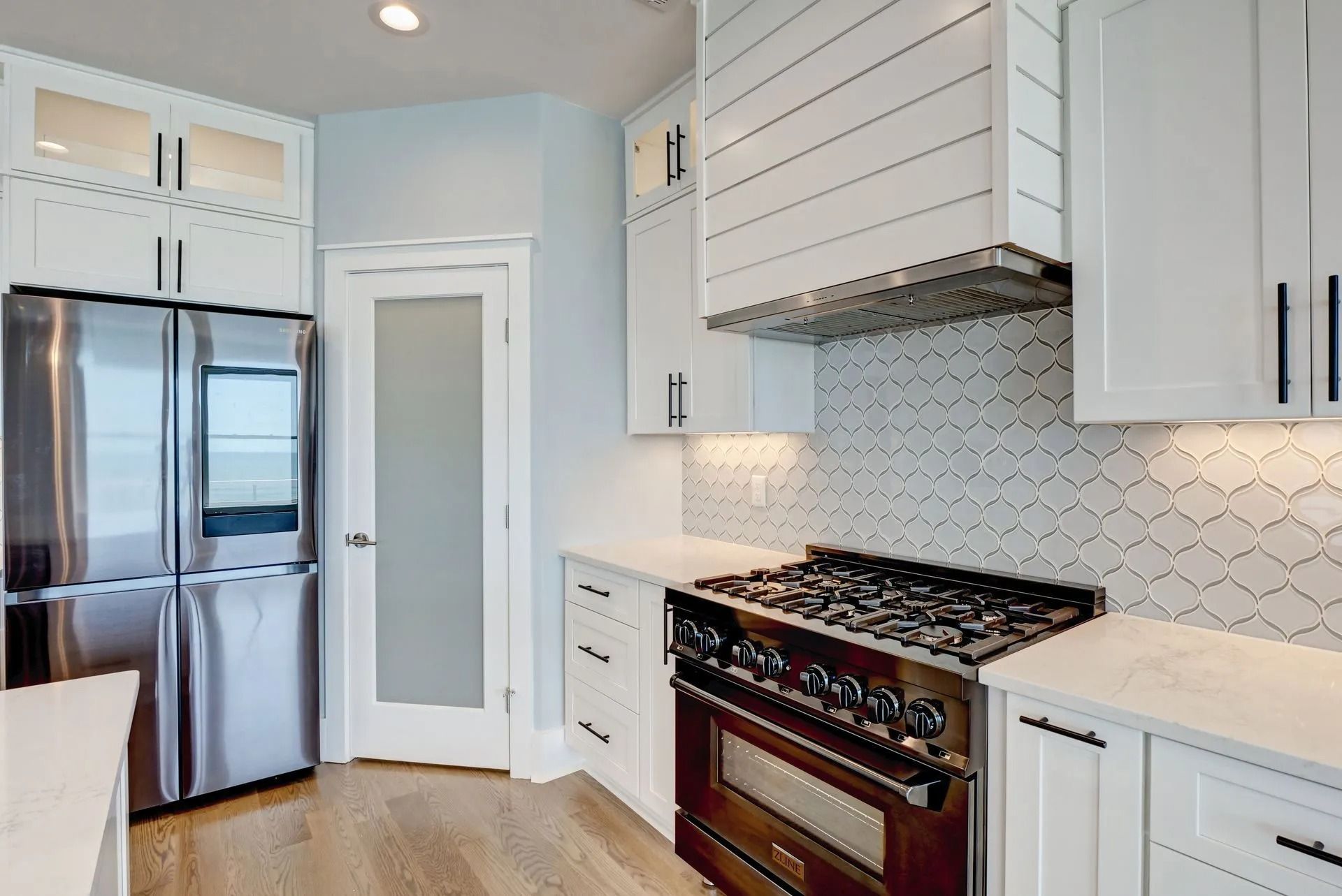 White kitchen with stainless steel appliances, stove, and light blue walls.