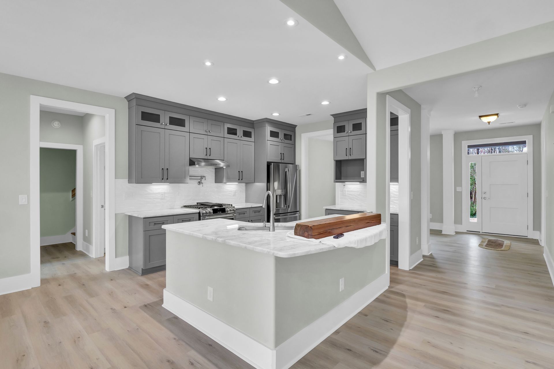 Gray kitchen with white countertops, island, and light wood floors.