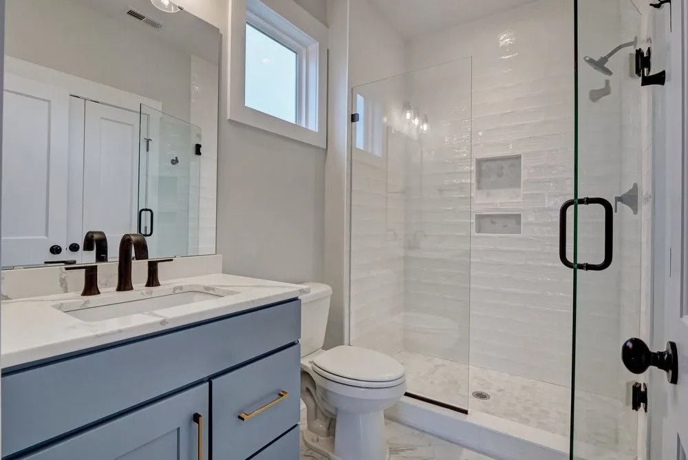 Bathroom with blue vanity, white toilet, and glass shower.