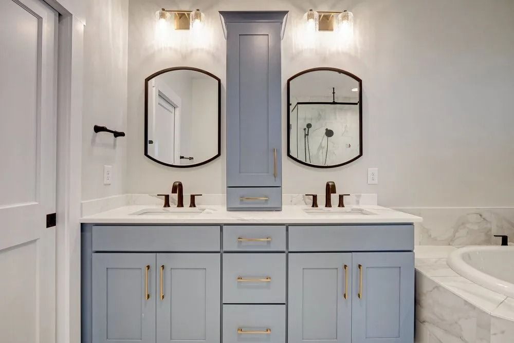 Bathroom with blue vanity, two mirrors, and brass fixtures.