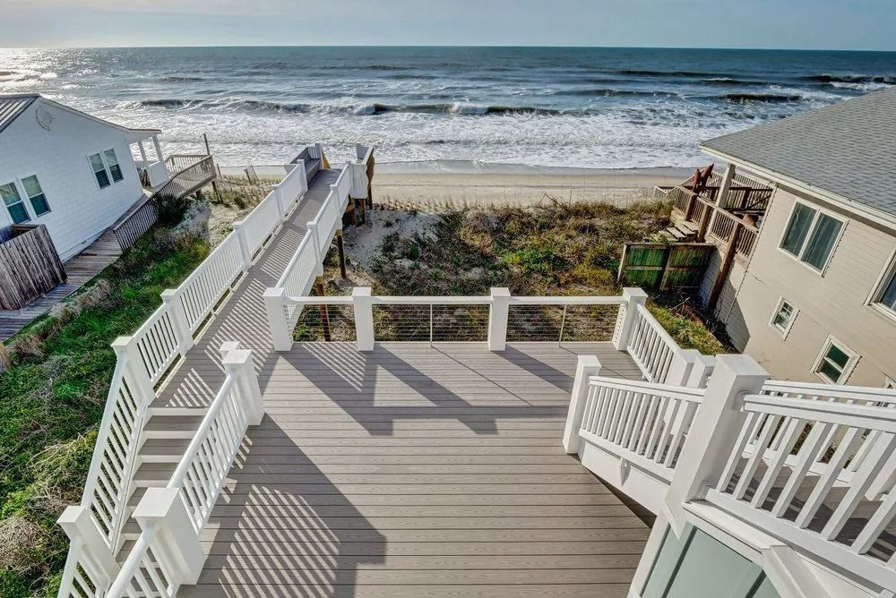 Beachfront homes with decks, ramp, and stairs leading to the ocean.