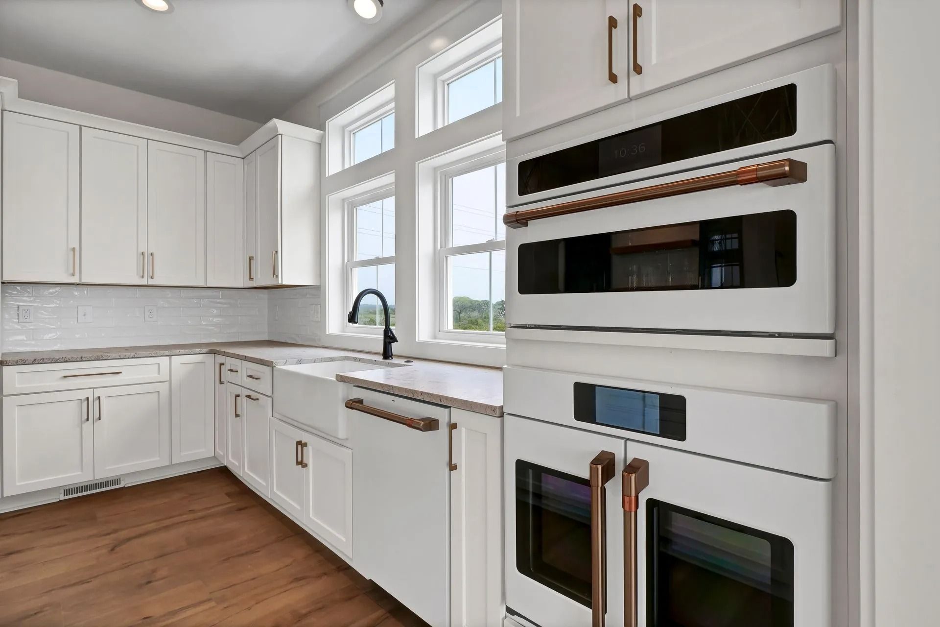 White kitchen with copper accents and a large window.