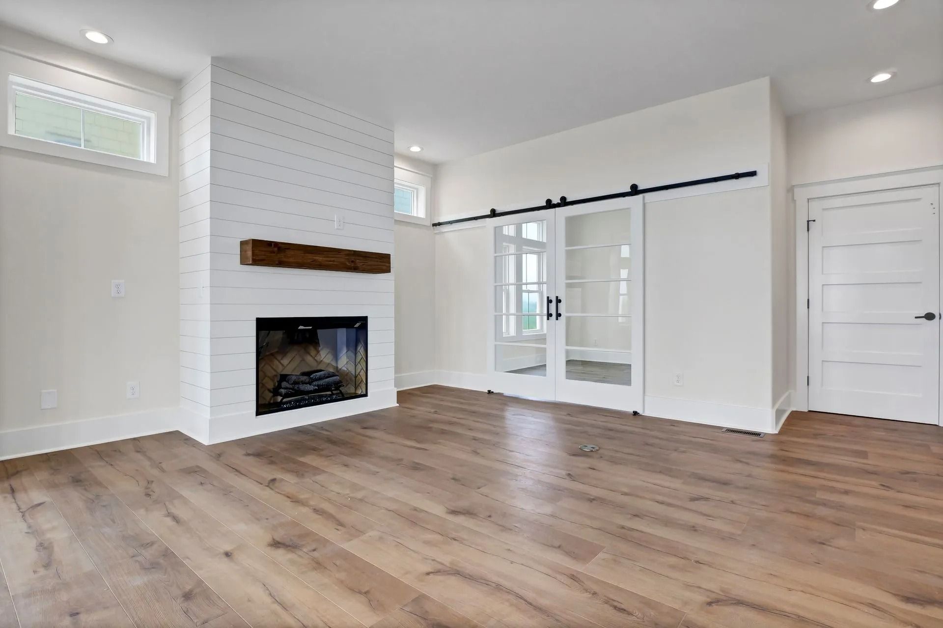 Empty living room with fireplace, sliding glass doors, and hardwood floors.