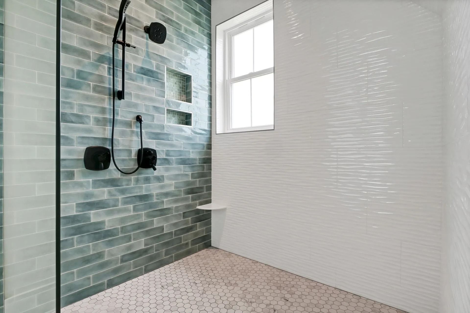 Shower with teal brick-like tile, white walls, black fixtures, small window, and mosaic floor.