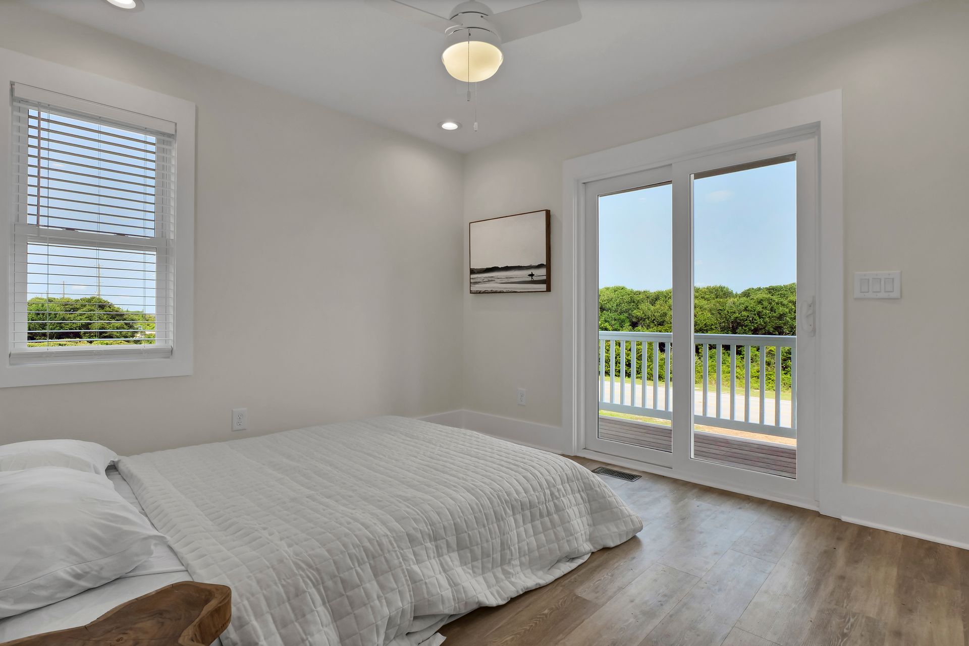 Bedroom with bed, sliding glass door to balcony, window with blinds.