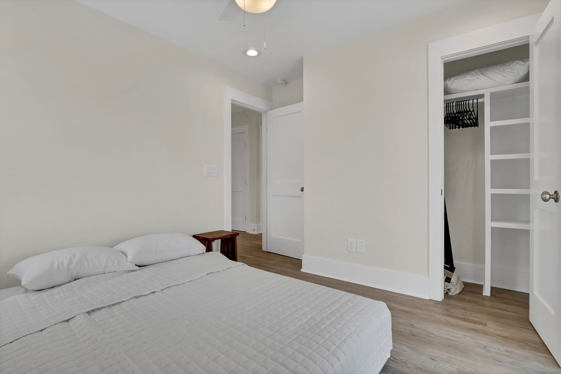 Bedroom with a bed, closet, and a door to a hallway, walls are white.