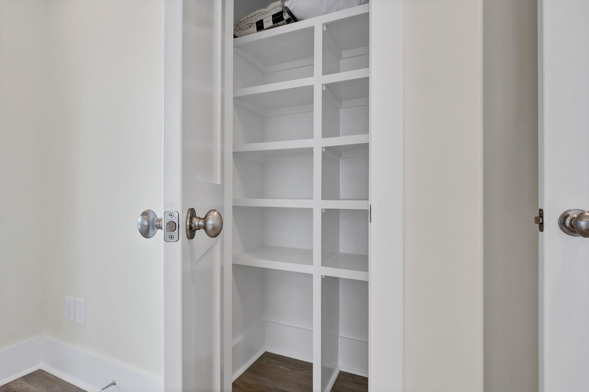 White-painted built-in closet with shelves. Interior door is open.