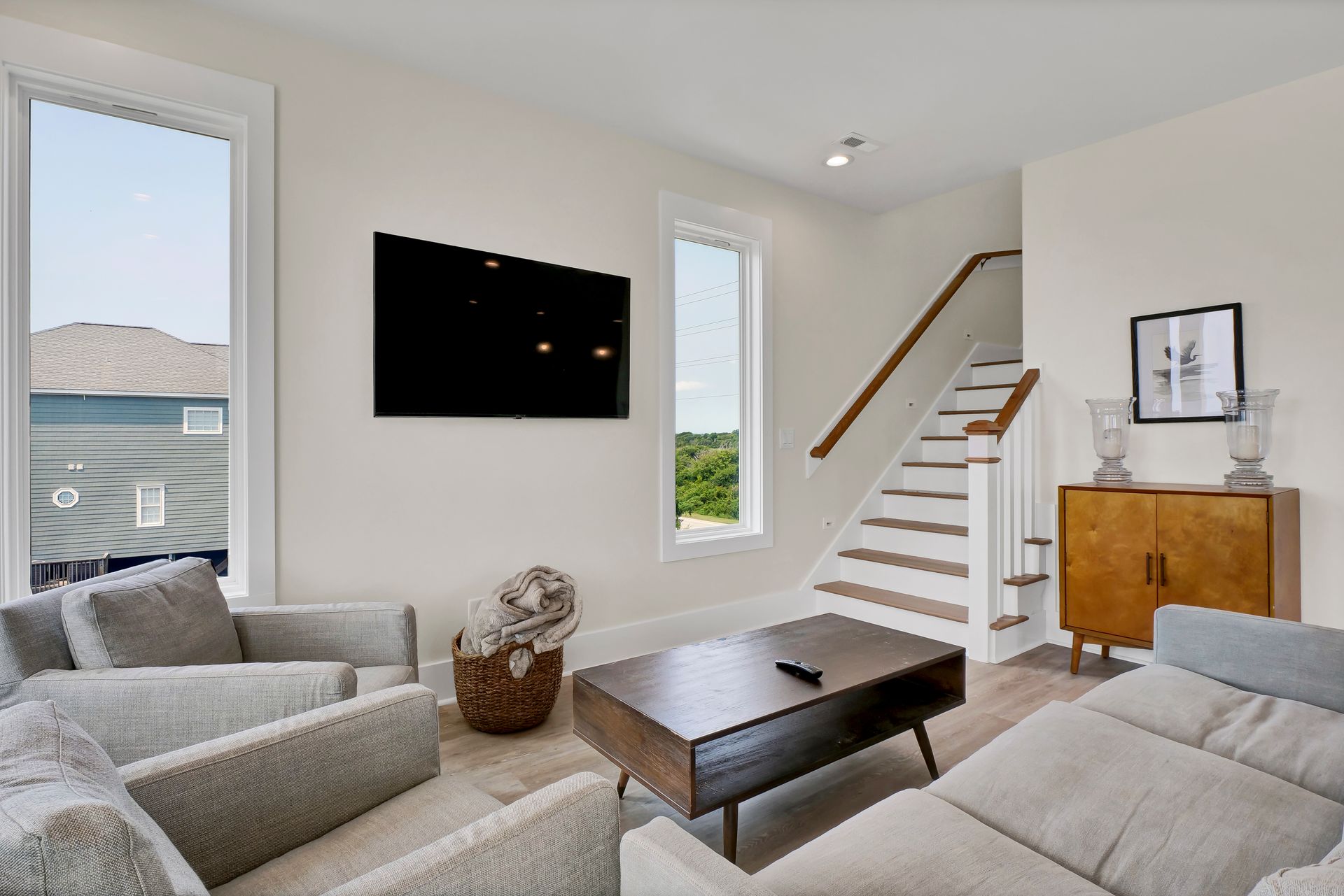 Living room with gray furniture, a wooden coffee table, and a staircase.