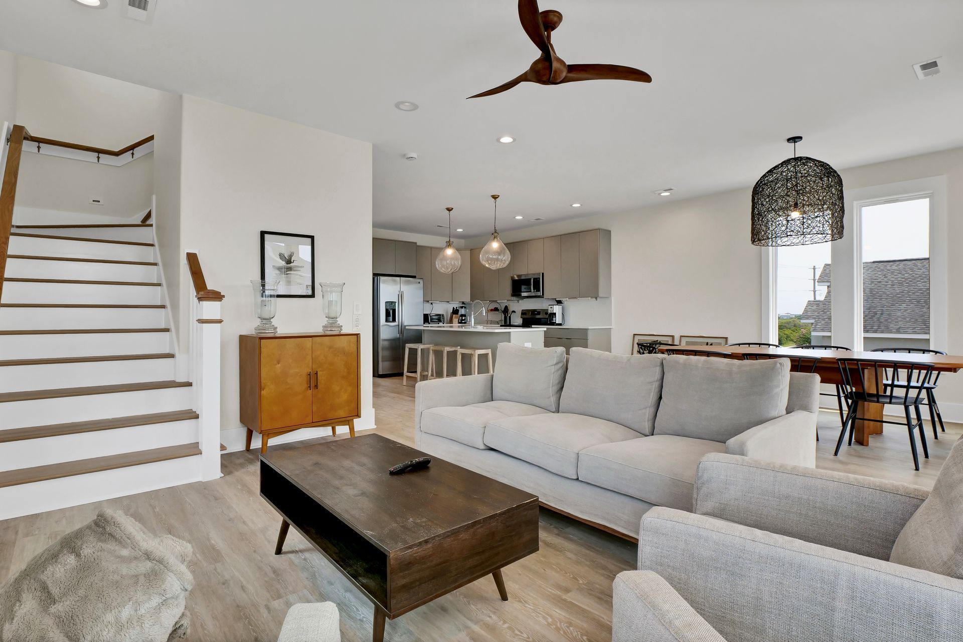 Living room with stairs, sofa, armchair, coffee table, and open kitchen.