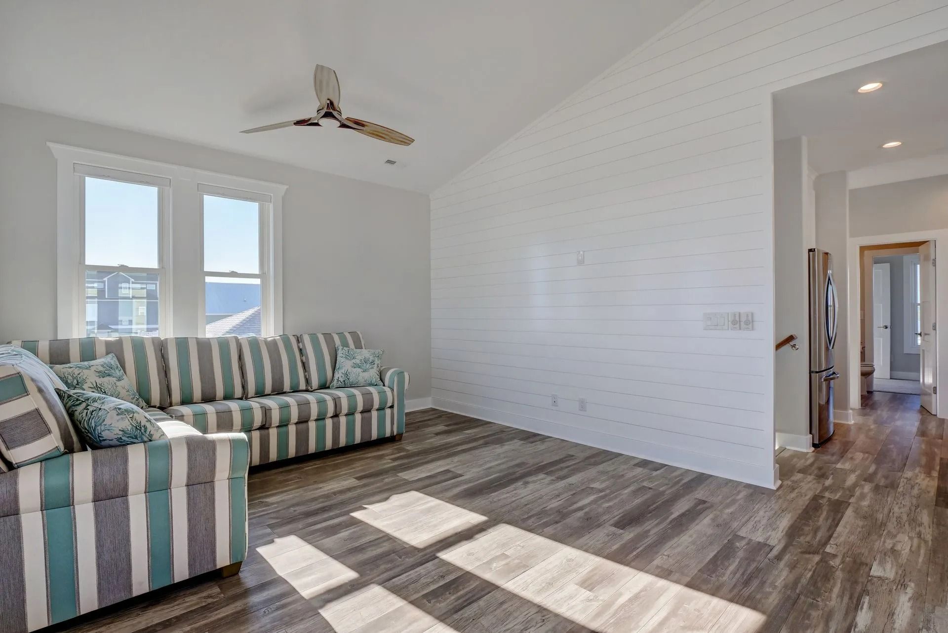 Living room with striped sofa, wood-look flooring, and white brick wall, with a view of water.