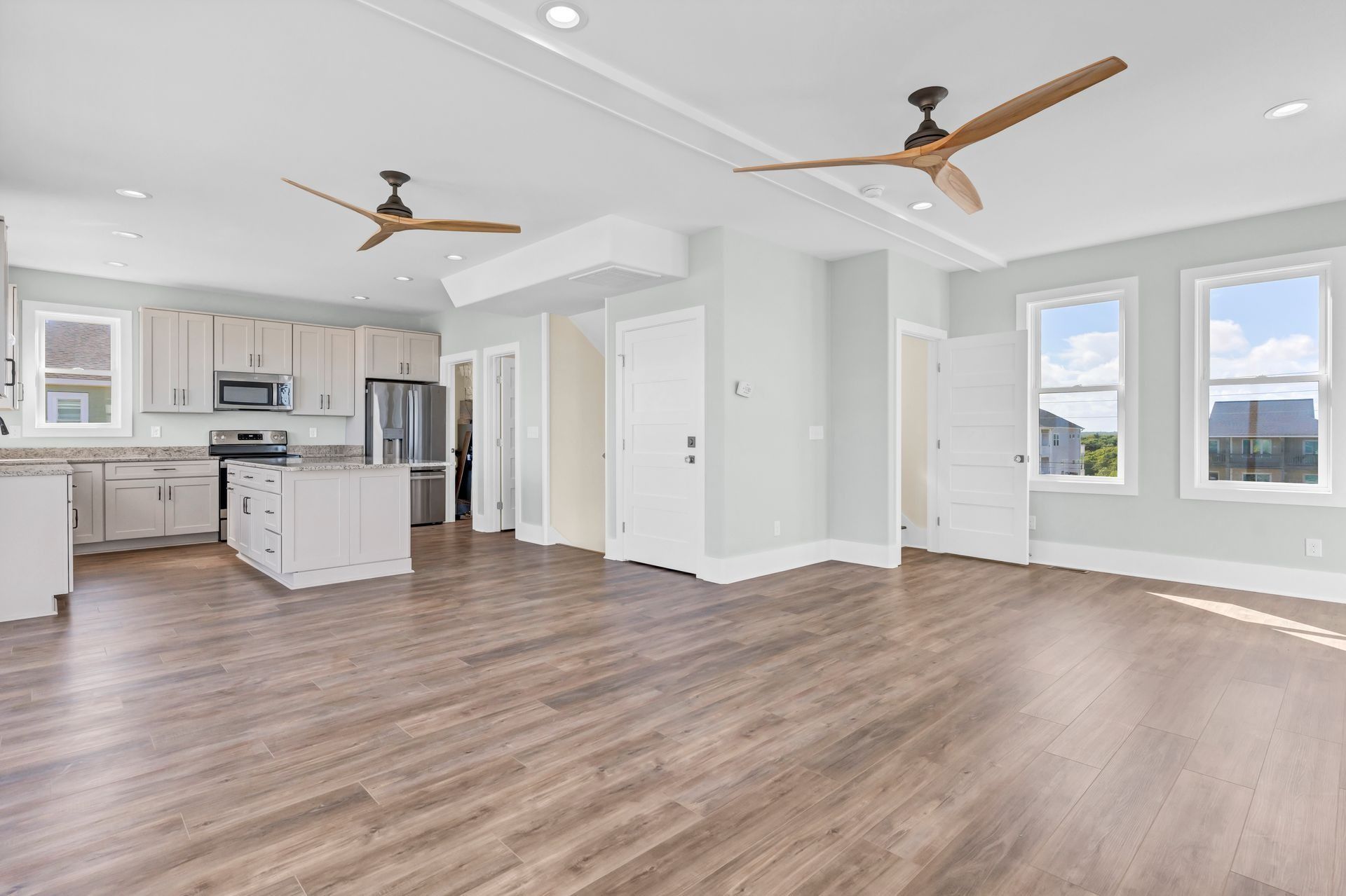 Spacious open-concept kitchen and living area with hardwood floors, light cabinets, and large windows.