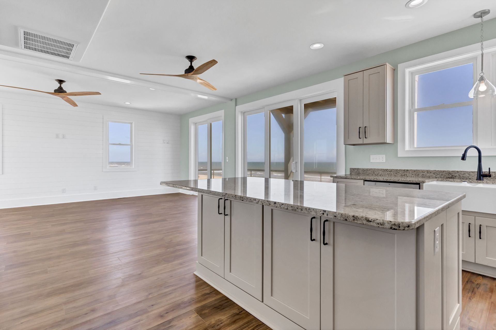 Kitchen with island, light cabinets, granite countertop, and sliding glass doors to outdoor view.